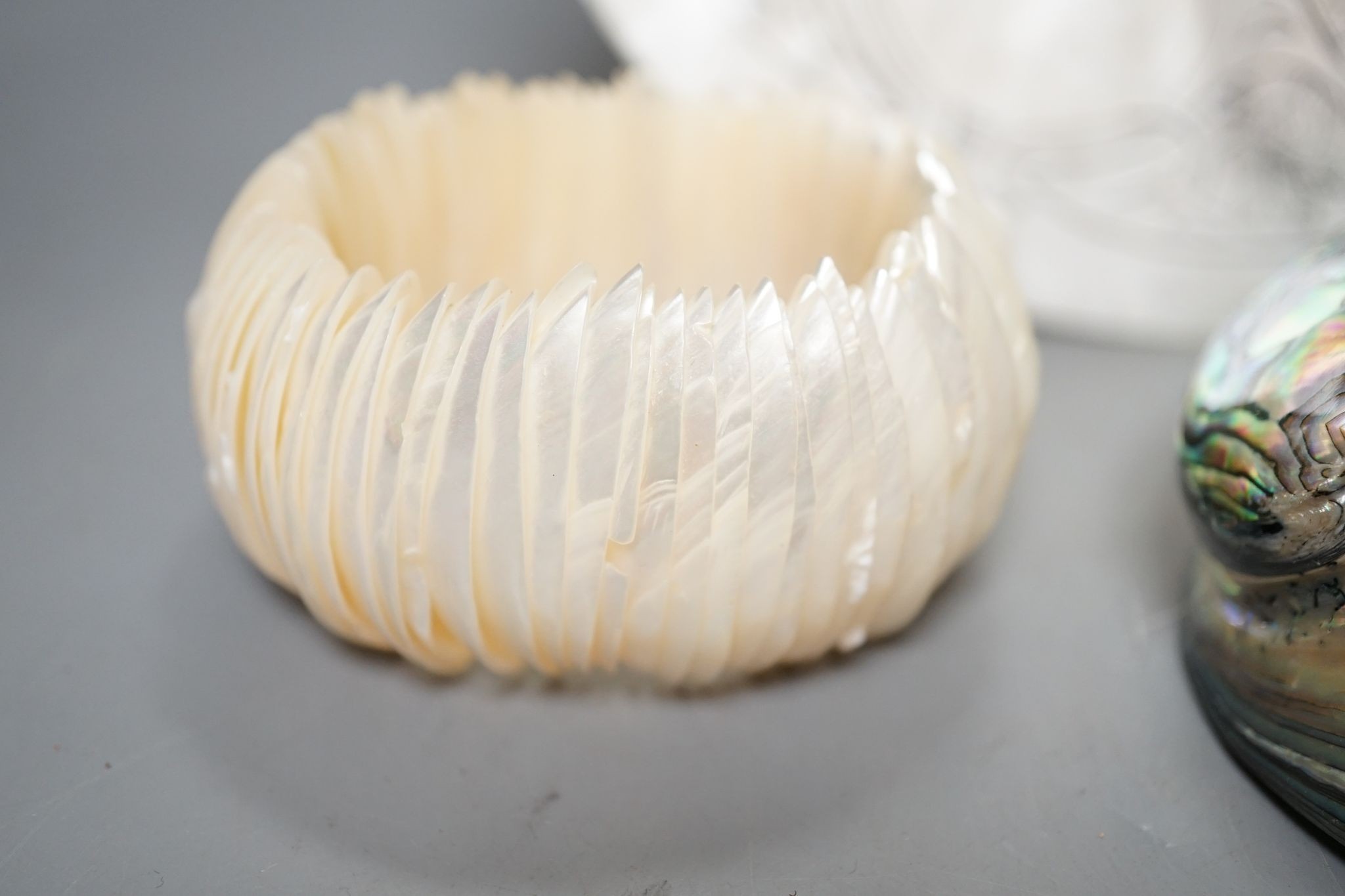 An engraved pearl shell, 22cm, a cylindrical box and bracelet, and two abalone shells